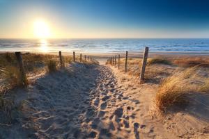 un chemin de sable menant à la plage au coucher du soleil dans l'établissement Hotel-Restaurant Unicum Elzenhagen, à Poeldijk