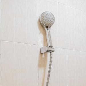 a shower head attached to a white tiled wall at Chola Inn at Nagoya Hill Batam Mitra RedDoorz in Jodoh