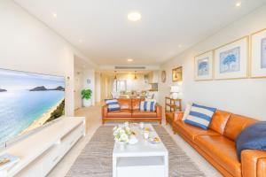 a living room with orange furniture and a view of the ocean at Cote D'Azur 42, 61 Donald St - complex pool, lift, linen, bed making and stunning water views in Nelson Bay