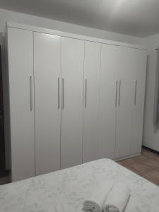 a white bedroom with white cabinets and two pairs of towels at Casa térrea aconchegante in Blumenau +35 photos