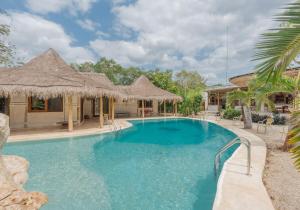 a swimming pool with blue water and straw umbrellas at Kasa UhMay Tulum in Francisco Uh May