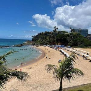a beach with a bunch of people in the water at Quarto e Sala Temporada no Rio Vermelho in Salvador +12 photos