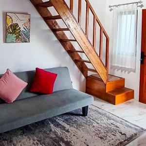 a living room with a couch with two red pillows at RedDoorz at Raujan Guesthouse Syariah Banjarmasin in Sungai Lutus +2 photos