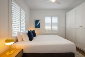 a white bedroom with a large white bed with pillows at Sunnyside On Burns - Central,Farmers Market, Beach in Byron Bay