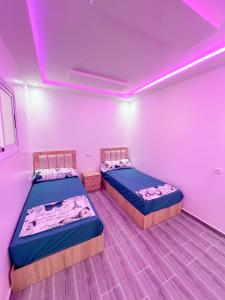 two beds in a room with purple lights at Visit Chamal - Costa Midnight in Oued Laou