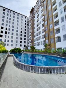a swimming pool in the middle of two buildings at Cozy Studio Skylounge Makassar Apartment in Manda