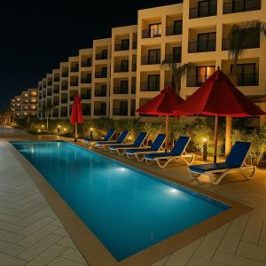 塞得港Relax and recharge in our luxurious Porto Said Chalets的酒店游泳池设有躺椅和遮阳伞