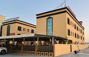 a large yellow building with a car parked in front of it at Al Nakheel Hotel Apartments in Ras al Khaimah