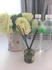 a vase with flowers in it next to water bottles at Elsa Tawau homestay near Airport in Tawau