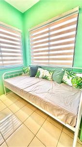 a bed sitting in a room with two windows at Enchanted Home - Near Enchanted Kingdom in Santa Rosa +7 photos