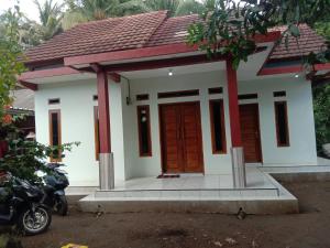 a small house with a motorcycle parked in front of it at Veni Homestay in Batukaras