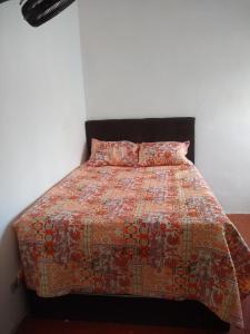 a bed with a quilt and two pillows on it at Quarto e Cozinha em Mongaguá in Mongaguá