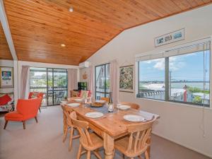 a dining room with a table and chairs at Hosts on the Coast The Harbourview Tairua in Tairua +20 photos