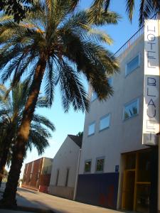 a large palm tree in front of a large building at Hotel Blauet by Bossh Hotels in El Prat de Llobregat
