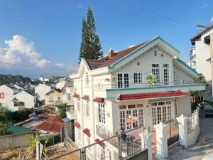 a white house with a fence in a city at Nhà Bi'x in Da Lat
