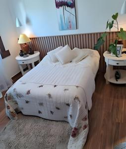 a bedroom with a large white bed with two tables at Casa paradisíaca em São Pedro da Aldeia RJ in São Pedro da Aldeia