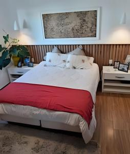 a bedroom with a large bed with a red blanket at Casa paradisíaca em São Pedro da Aldeia RJ in São Pedro da Aldeia