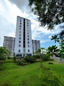 a tall building with a green lawn in front of it at 1BR Skylounge Apartment Makassar in Manda