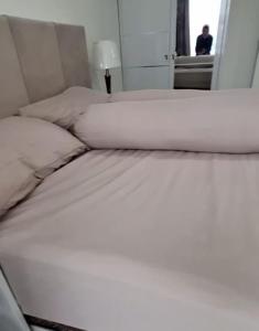 a bed with white sheets and pillows in a room at 1BR Skylounge Apartment Makassar in Manda