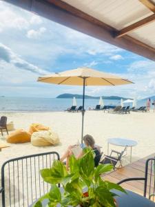 a woman sitting in a chair under an umbrella on the beach at Seaside Cenang in Pantai Cenang
