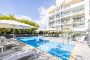 a swimming pool with chairs and umbrellas next to a building at Cote D'Azur 42, 61 Donald St - complex pool, lift, linen, bed making and stunning water views in Nelson Bay