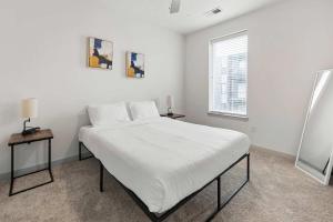 a white bedroom with a large bed and two tables at Stunning Nulu 1BR CozySuites 09 in Louisville +29 photos