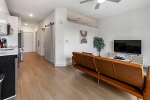 a living room with a couch and a flat screen tv at Stunning Nulu 1BR CozySuites 10 in Louisville