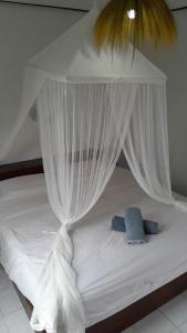 a bed with white mosquito netting on top of it at Bukit Kembar Ecotourism in Gitgit