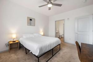 a white bedroom with a bed with a ceiling fan at Modern Nulu 2BR CozySuites 07 in Louisville