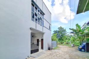 a white building with a car parked next to it at RedDoorz Syariah Near Alun-Alun Kudus in Kudus