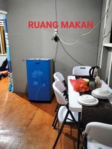 a table with white chairs in a room with arowing marani sign at Ayu Islamic Homestay in Ternate