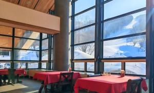 Un restaurante con mesas rojas y un gran ventanal. en Berjaya Hakkoda Ski Resort, en Aomori