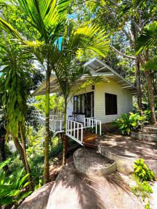 una pequeña casa blanca con palmeras delante en Dragon Soul Retreat Center, en Ko Pha Ngan
