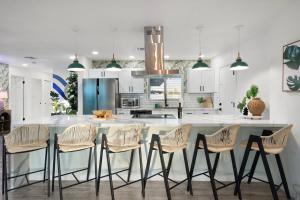 a kitchen with white cabinets and a counter with stools at Palm haus the experience in Phoenix