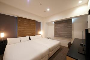 a bedroom with a large white bed and a desk at Sotetsu Fresa Inn Nihombashi-Ningyocho in Tokyo