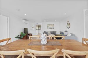 comedor y sala de estar con mesa de madera en Bailey's Beach House, en East Ballina