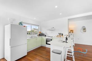 Il comprend une cuisine équipée d'appareils électroménagers blancs et d'un réfrigérateur blanc. dans l'établissement Stella LJHooker Yamba, à Brooms Head 23 autres photos