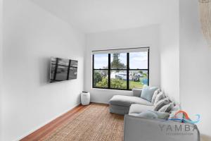 un salon avec un canapé et une fenêtre dans l'établissement Stella LJHooker Yamba, à Brooms Head