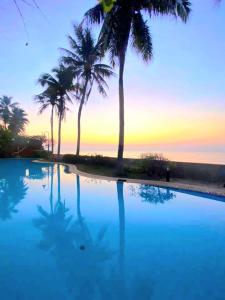 a swimming pool with palm trees and a sunset at Dar's Haven Cha-Am in Cha Am