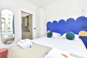 una camera da letto con un letto con testiera blu e uno specchio di Charming and cosy flat next to the Eiffel Tower a Parigi