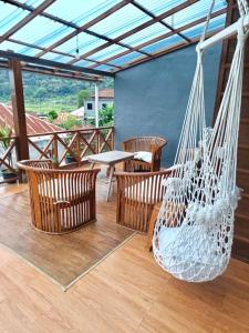 a porch with a hammock and chairs and a table at Woody House in Bedugul