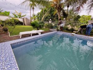 a swimming pool in a yard with two men working at Beach Studio wih integrated Kitchen in Kribi