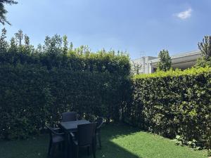 a table and chairs in a yard with a hedge at Monolocale con giardino privato e cucina completa in Bergamo