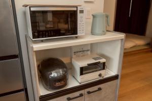 a microwave and a toaster oven on a shelf at New 充実設備&コスパ&快適重視の宿!空港美瑛富良野スキー場4ヵ所アクセス良!キッズエリア大人気 in Asahikawa +39 photos