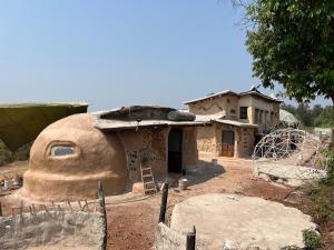 ein kleines Haus mitten auf einem Feld in der Unterkunft Mrudaranya the Earth Tech Pod in Panchgani