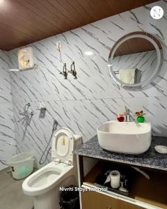 a bathroom with a sink and a toilet and a mirror at Nivriti Stays in Kanatal