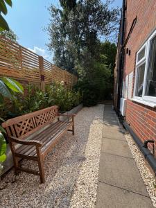 a wooden bench sitting next to a brick building at Aeolian House in Cranleigh