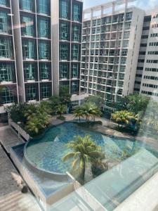 a large swimming pool with palm trees in front of tall buildings at Myra Guesthouse Bohemian Style Mutiara Ville Duplex Apartment in Cyberjaya