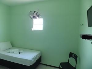 Habitación blanca con cama y silla en Pousada Cariri en Juazeiro do Norte