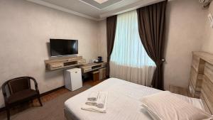 a hotel room with a bed and a television at Гостиница S-Namangan in Irvadan